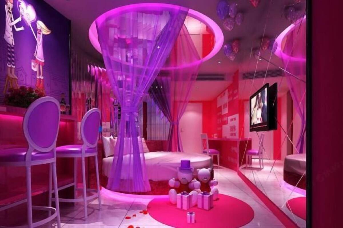 A room with a central circular structure, white chairs, and a television on the wall.