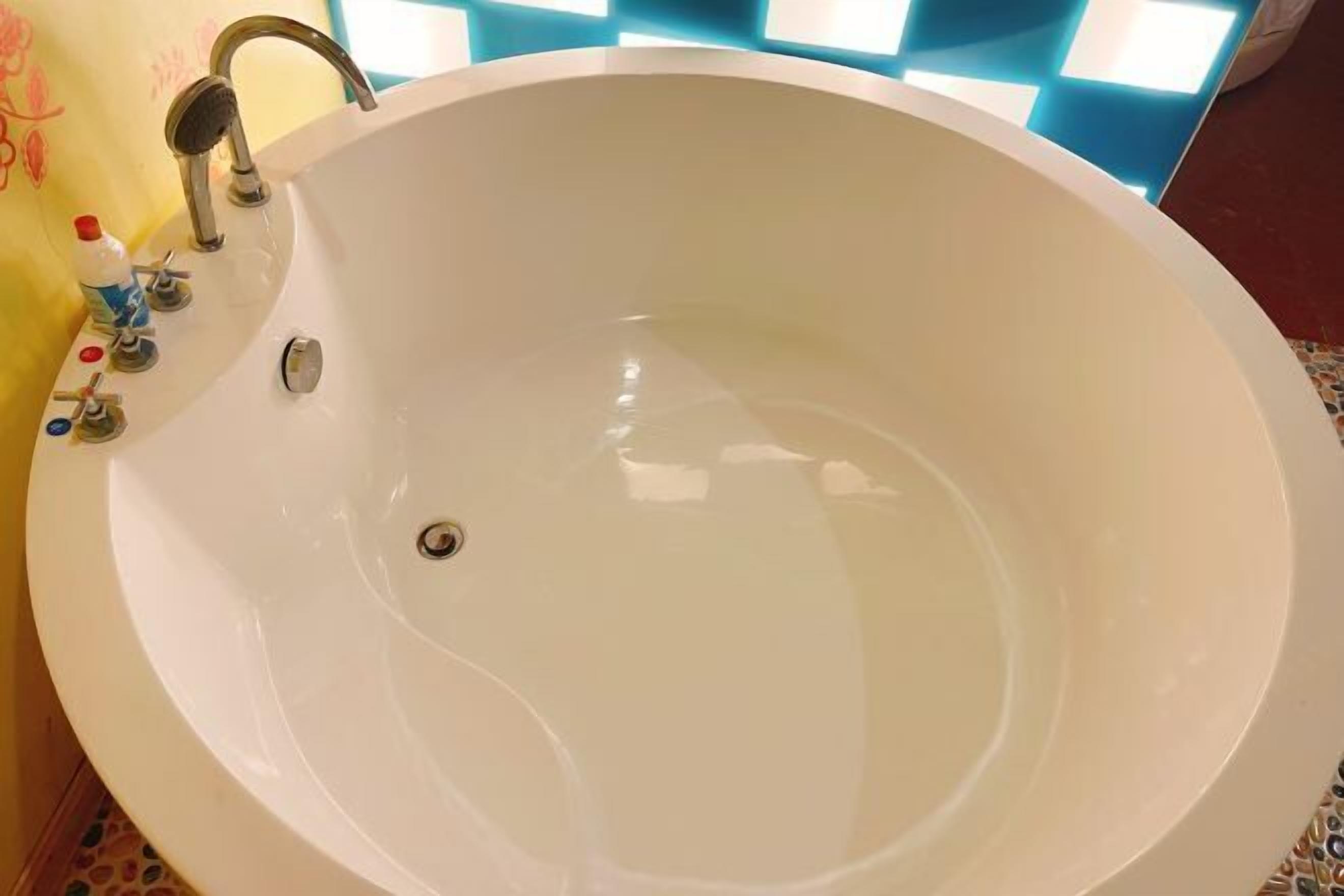 A large, round white bathtub with a single faucet and a drain.
