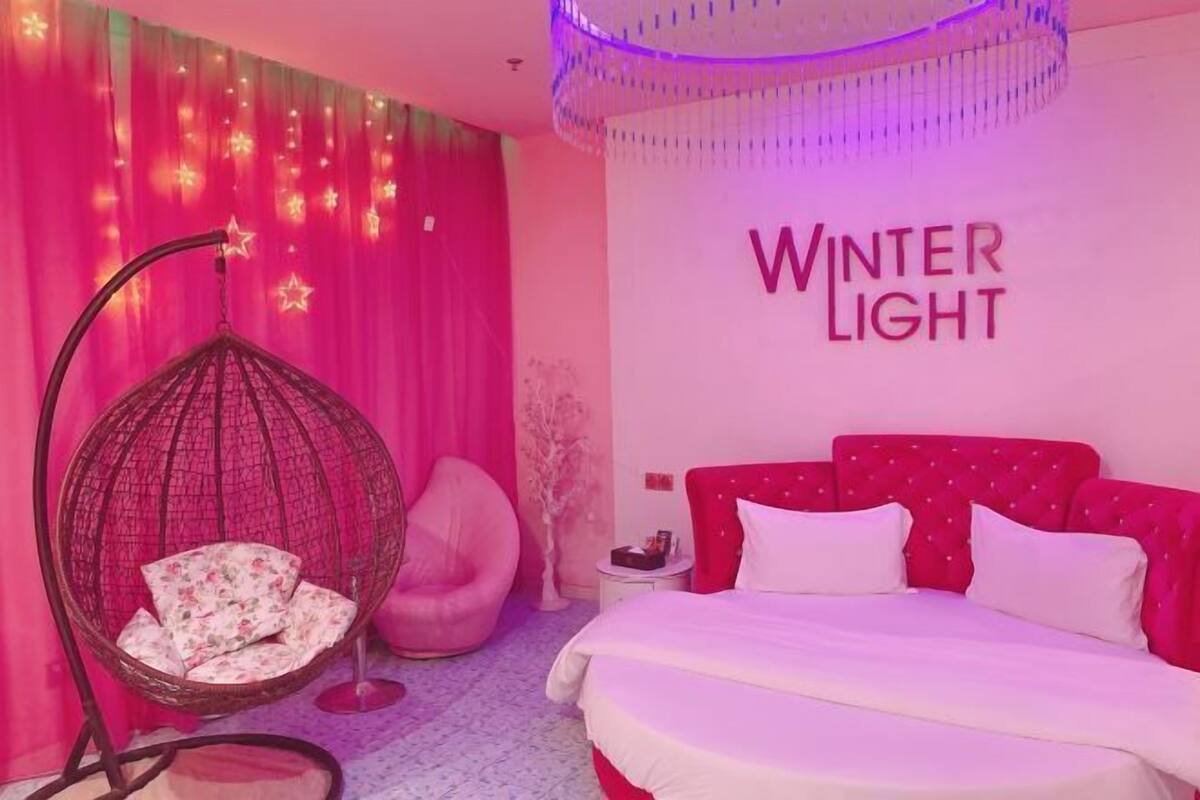A bedroom with a bed, a hanging chair, and a wall with 'Winter Light' text.
