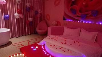 Una camera da letto con un letto, tende, una sedia e un elemento decorativo al muro.