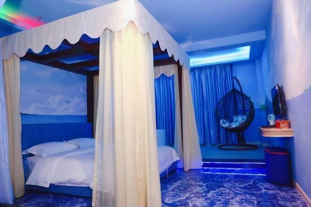 A bedroom with a canopy bed, a hanging chair, and a small table with items on it.