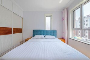 Een slaapkamer met een bed, een raam en uitzicht op gebouwen.