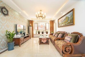 A spacious living room with a large sofa set, a TV, and a chandelier. - Qingdao Yijian Qingxin Whole Vision Apartment (Qingdao)