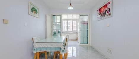 Un comedor con una mesa de vidrio, sillas de madera y piso de color claro.