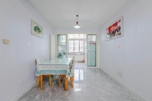 A dining area with a glass table, wooden chairs, and a light-colored floor. - Qingdao Yijian Qingxin Whole Vision Apartment (Qingdao)