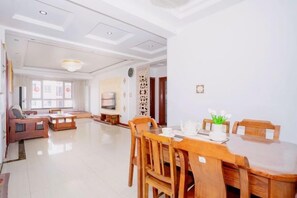 A spacious living room with a dining area, a sofa set, a TV, and a decorative wall. - Qingdao Yijian Qingxin Whole Vision Apartment (Qingdao)