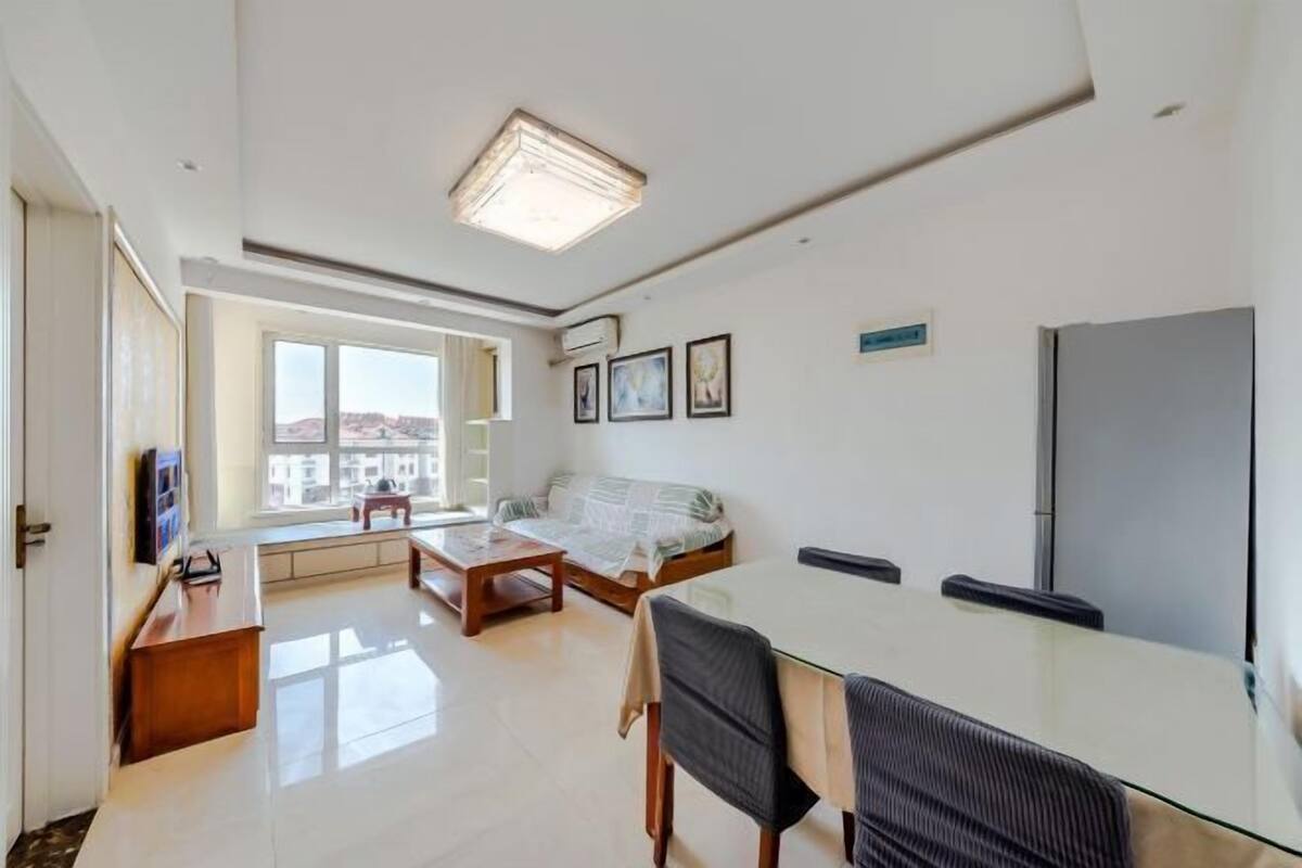 A modern living room with a sofa, a dining table, and a TV.
