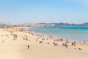 A beach with a lifeguard tower, sandy shore, and buildings in the background.