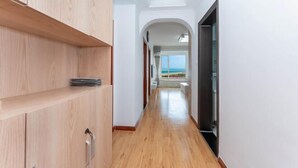 A hallway with wooden flooring, white walls, and a view of the sea through an arched doorway. - Qingdao Yijian Qingxin Whole Vision Apartment (Qingdao)