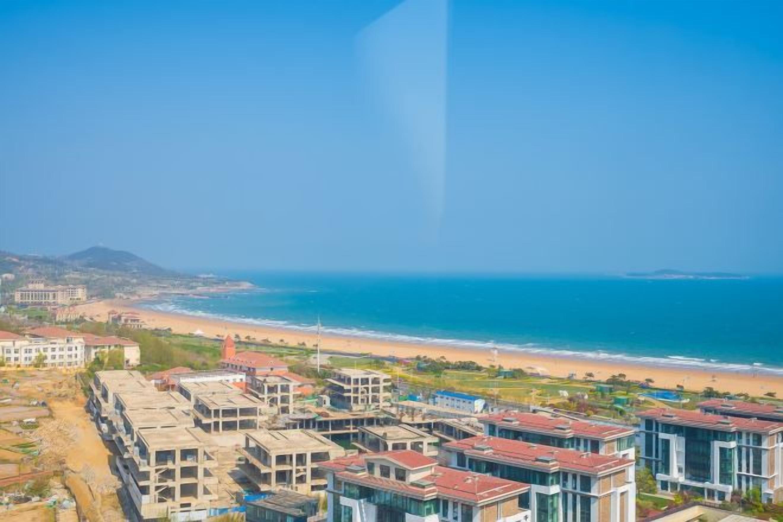Un área residencial costera con edificios, una playa y el océano.