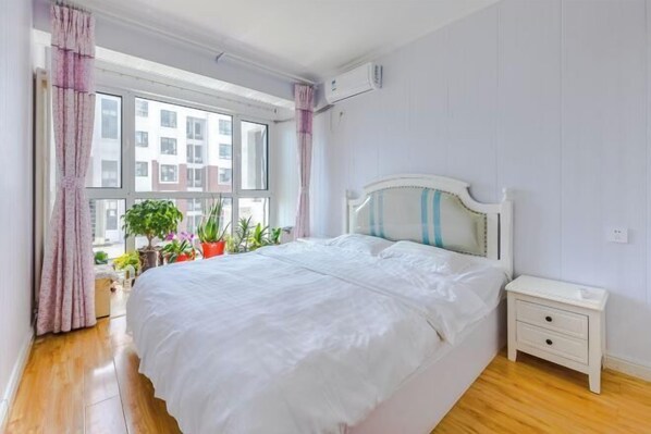 A bedroom with a bed, bedside table, and potted plants.