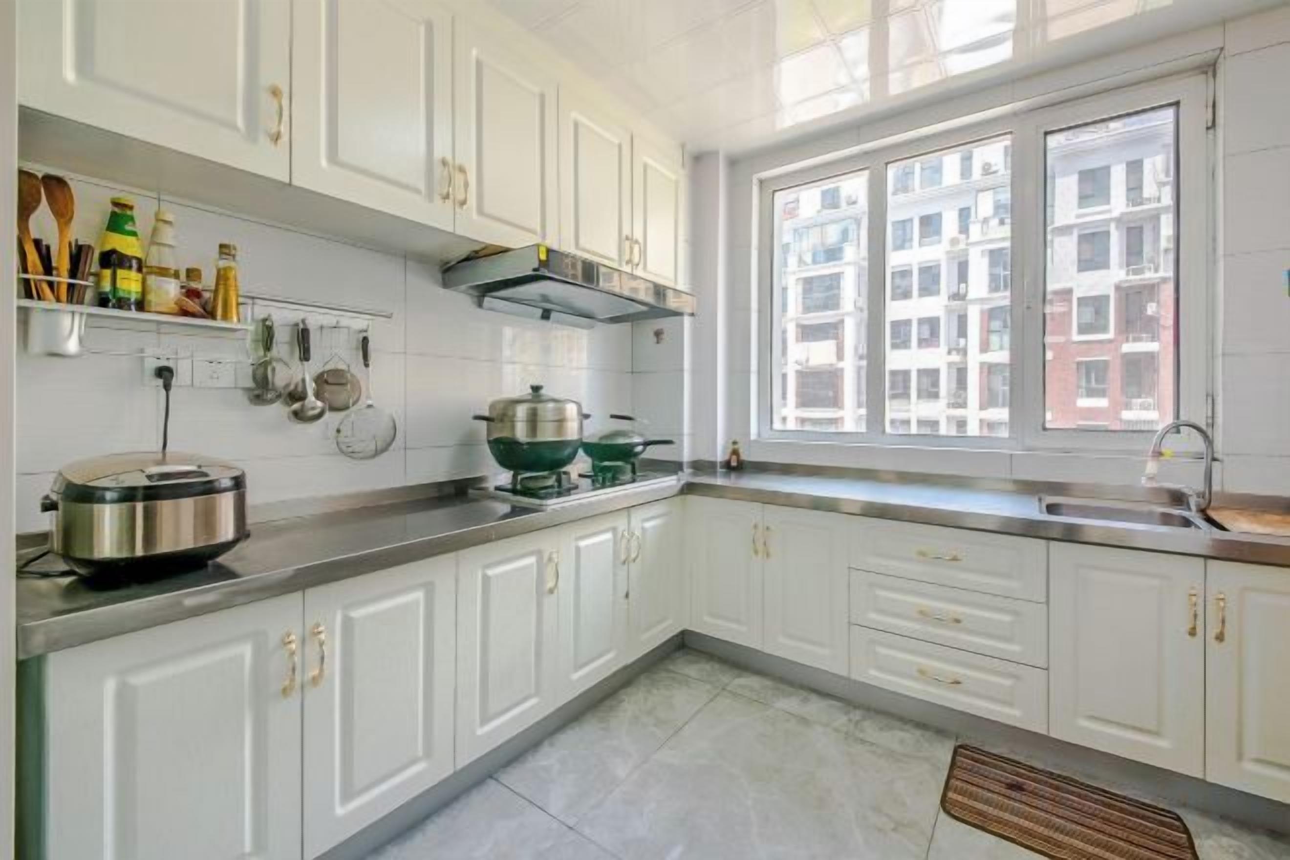 A kitchen with white cabinets, a window with a view of buildings, and a stove.