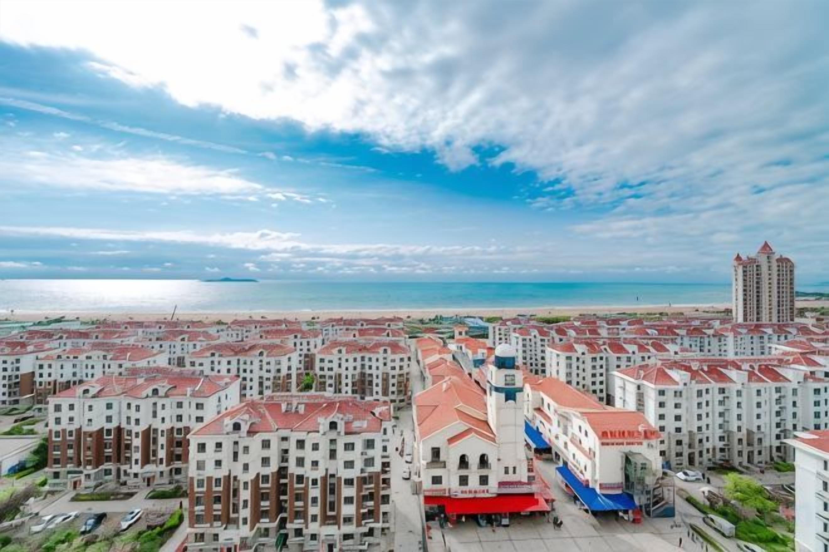 A residential area with multiple apartment buildings, a central plaza, and a view of the beach.