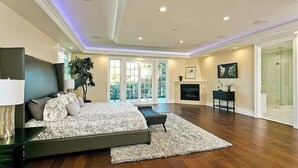A spacious bedroom with a large bed, a fireplace, and a view of the outdoors. - Stunning Sherman Oaks Home minutes from all LA has to offer. Pool Oasis! (Los Angeles)