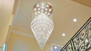 A grand chandelier hanging from the ceiling in a well-lit room with a staircase featuring ornate metal railings. - Stunning Sherman Oaks Home minutes from all LA has to offer. Pool Oasis! (Los Angeles)