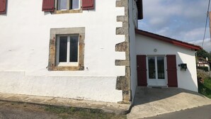 Un bâtiment blanc avec des volets rouges et une façade en pierre.