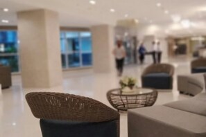 A modern lobby with wicker chairs, a sofa, and a coffee table. - Chin's Place Sea Residences MOA (Pasay)