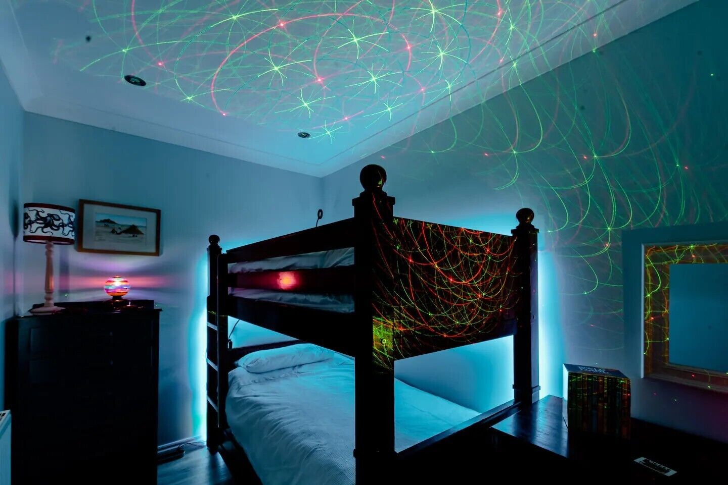 Un dormitorio con una cama individual doble, un escritorio con lámpara y una pared con un cuadro enmarcado.