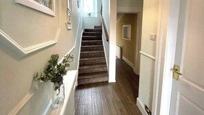 Ein Flur mit einer Treppe, einer Tür und einem Wandbild.