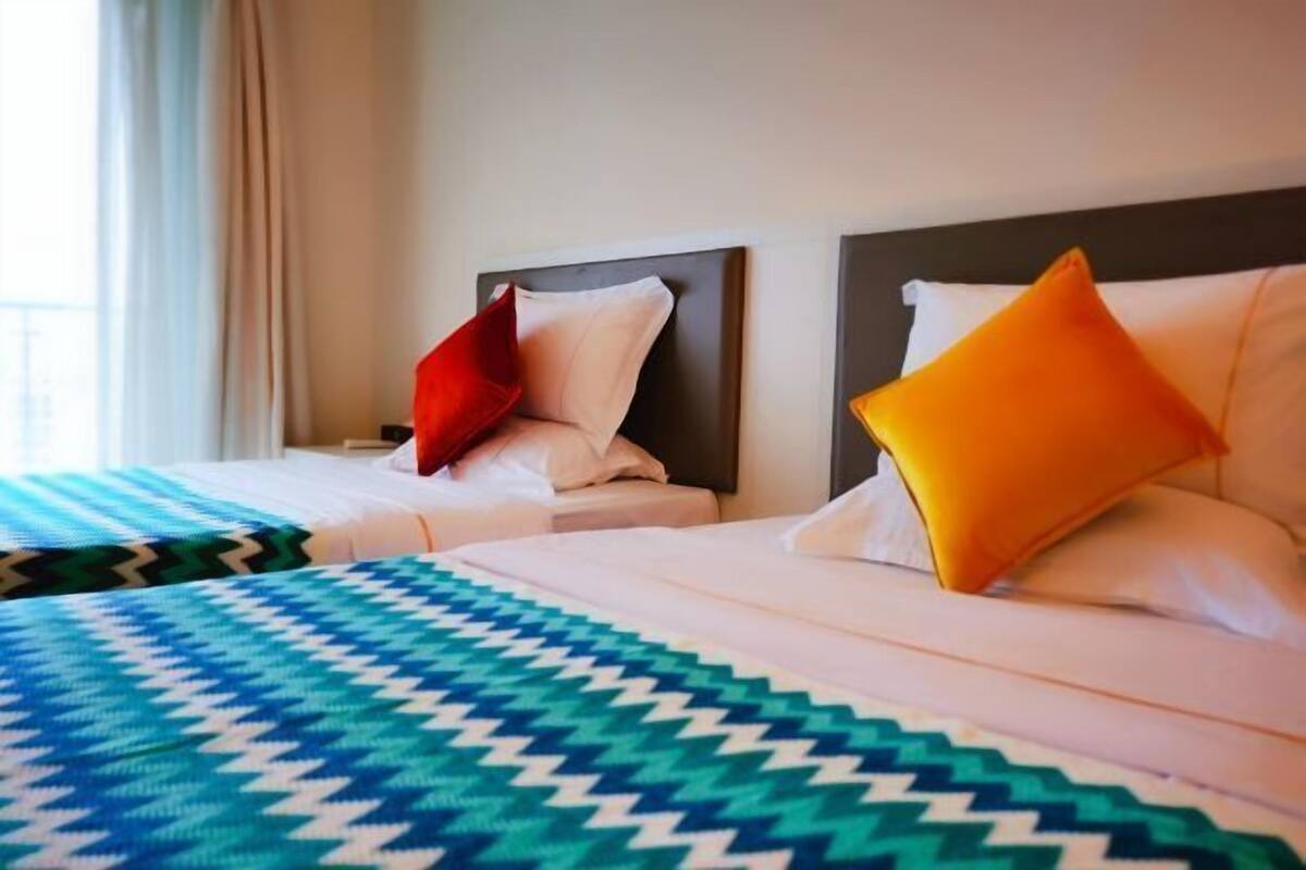 Ein Hotelzimmer mit zwei Betten, jeweils mit Kopfteil, einem gemusterten Bettbezug und Kissen.