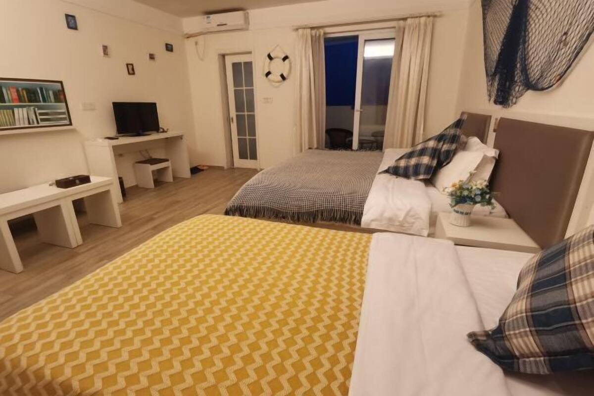 Ein Hotelzimmer mit Bett, Schreibtisch, Fernseher und Blick ins Freie.
