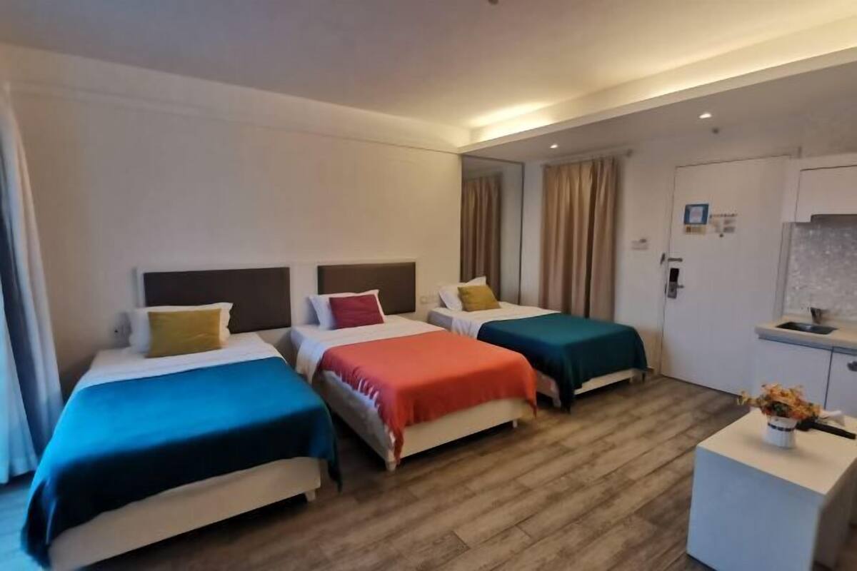 Ein Hotelzimmer mit drei Betten, einer kleinen Küchenzeile und einem Badezimmer.