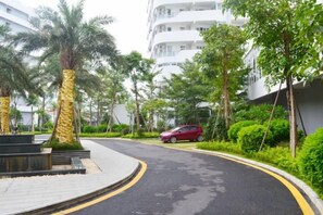 A curved road with a red car parked on the side, surrounded by greenery and palm trees. - Hongshuwanpan Holiday Hotel (Huidong)
