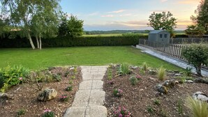 A garden pathway leading to a grassy area with a wooden fence and a shed in the background. - Villa de Charme Avec Piscine - Idéale Pour des Vacances en Famille ou Entre Amis (Julienne)
