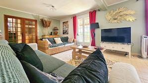 A living room with a sofa, a television, a lamp, and a decorative plant. - Villa de Charme Avec Piscine - Idéale Pour des Vacances en Famille ou Entre Amis (Julienne)