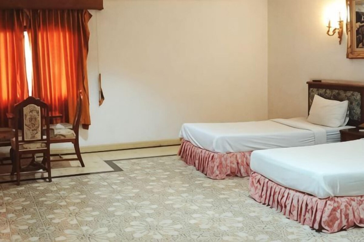 Une chambre d’hôtel avec deux lits, une chaise, une table et un sol à motifs.
