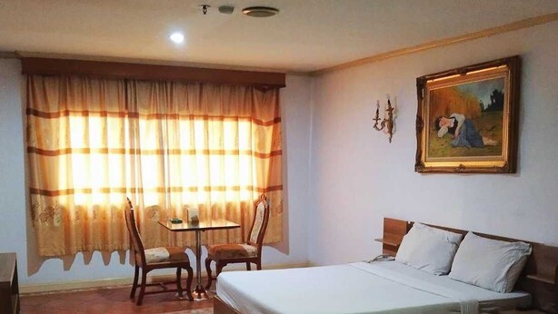 A hotel room with a bed, a table, two chairs, and a painting on the wall. - OYO 75466 13 Coins Bang Yai Hotel (Bang Yai)