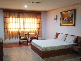 Una habitación de hotel con una cama, una mesa, dos sillas y un cuadro en la pared.
