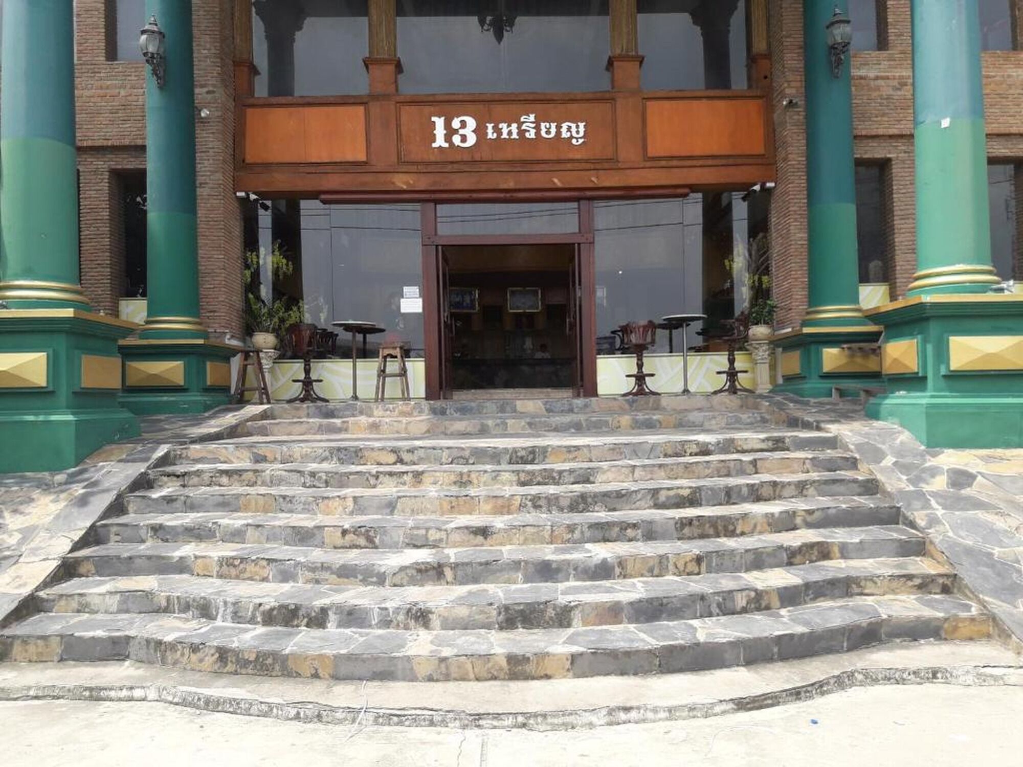 Une entrée d'immeuble avec une enseigne indiquant le numéro « 13 » et un escalier menant à cette entrée.
