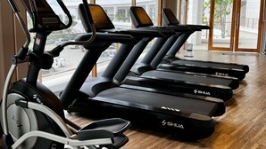 Ein Fitnessstudio mit mehreren Laufbändern, einem Ergometer und einem Rudergerät.