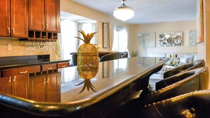 A kitchen with wooden cabinets, a bar area, and a decorative pineapple centerpiece.