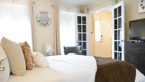 A hotel room with a large bed, a TV, a chair, and a wardrobe.
