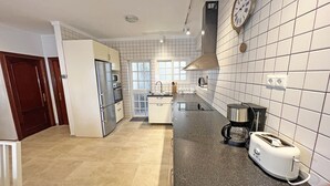 A modern kitchen with white tiled walls, stainless steel appliances, and a black granite countertop.
