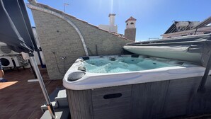 A hot tub with a stone wall and a chimney in the background.