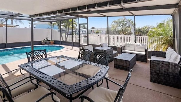 Une terrasse extérieure avec une table en verre, des meubles en osier et une piscine.