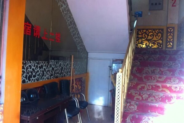 A staircase with ornate railings, a patterned wall, and a room with a desk and chairs. - Xinyuan New Super 8 Express Hotel (Xinyuan)
