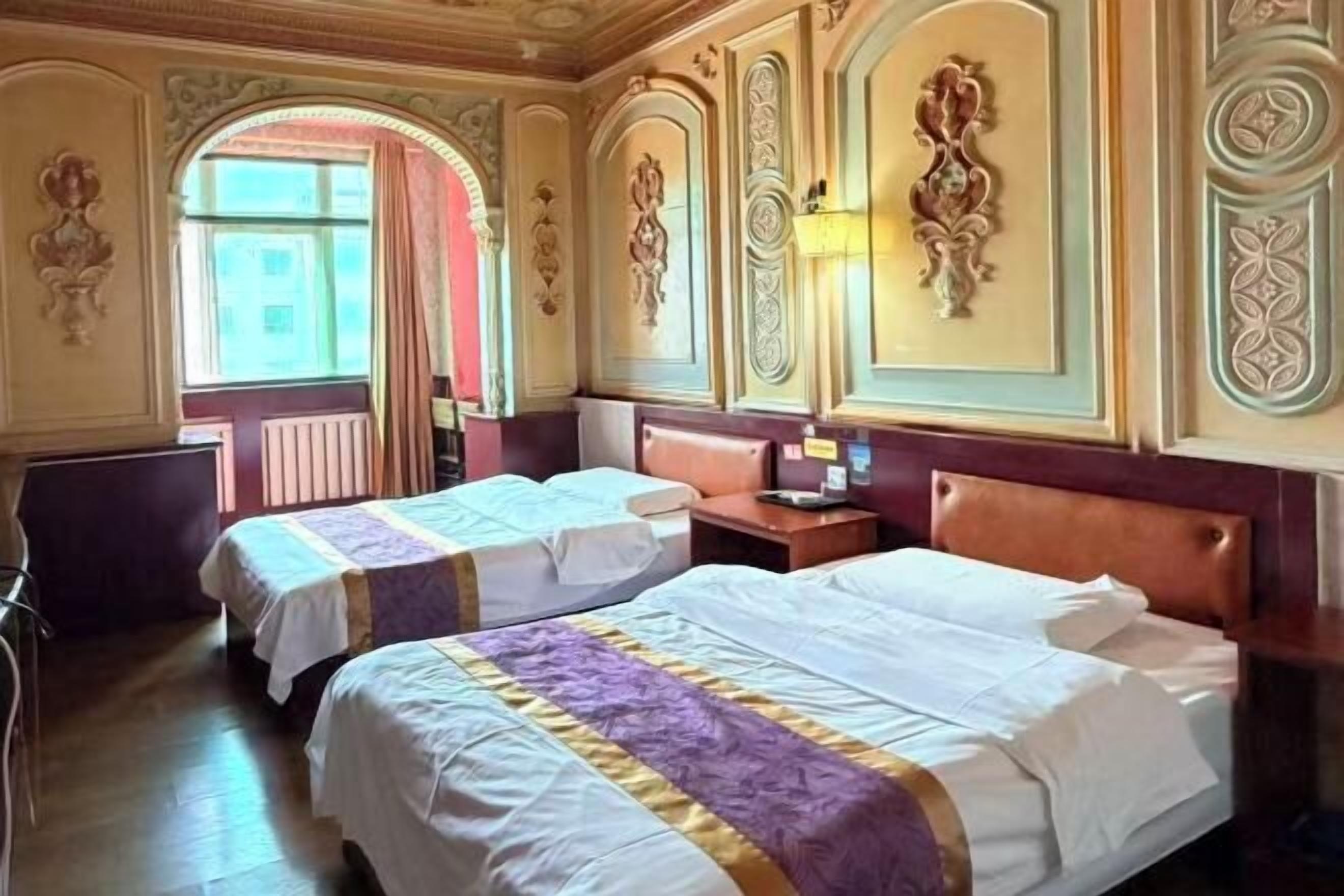 Una habitación de hotel con dos camas, un escritorio, una silla y una ventana con cortinas.