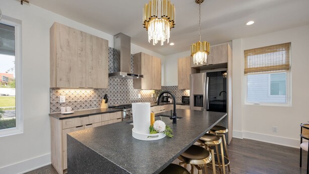 A modern kitchen with a central island, bar stools, and pendant lighting. - Ultra Heated Rooftop Pool! Arcade, Elevator, EV Charger, Sleeps 12, Full Home (Nashville)