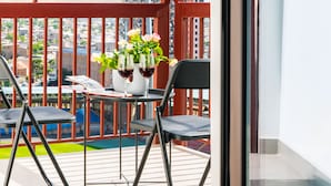 Ein Balkon mit Tisch, zwei Stühlen und einer Blumenvase.