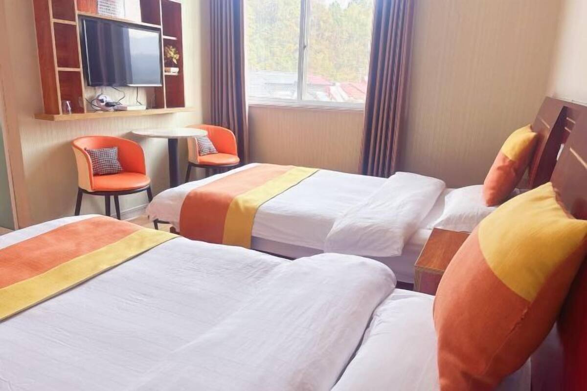 Een hotelkamer met twee bedden, een televisie en een kleine tafel met stoelen.