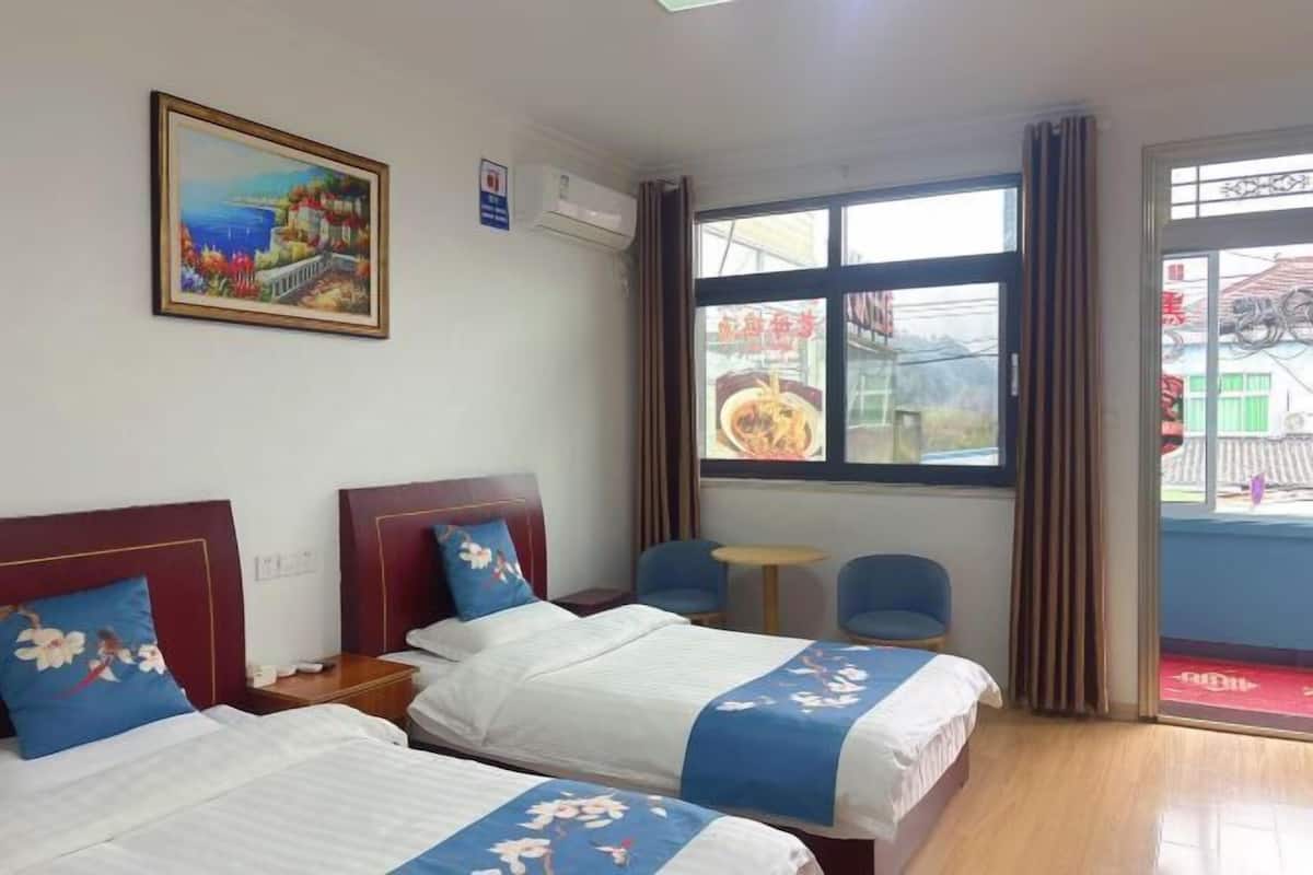 Een hotelkamer met twee bedden, een schilderij, een raam met uitzicht en een klein tafeltje.