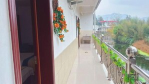 A corridor with a tiled floor, a metal railing with greenery, and a view of a river and mountains in the distance. - Ningguo Annan Sichuan-Tibet Line Fengbanzhan (Ningguo)