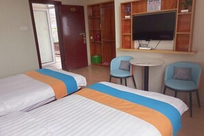 Een hotelkamer met twee bedden, een televisie, een klein tafeltje en twee stoelen.