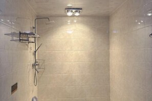 Een moderne douche met een glazen cabine, een handdouche en een muurbevestigde kraan.