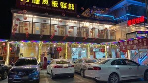 A building with a sign that reads "万惠风板坚果" and "万惠住客". There are cars parked in front, and the building has multiple windows. - Ningguo Annan Sichuan-Tibet Line Fengbanzhan (Ningguo)