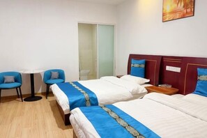 Een hotelkamer met twee bedden, een tafeltje, twee stoelen en een schilderij aan de muur.